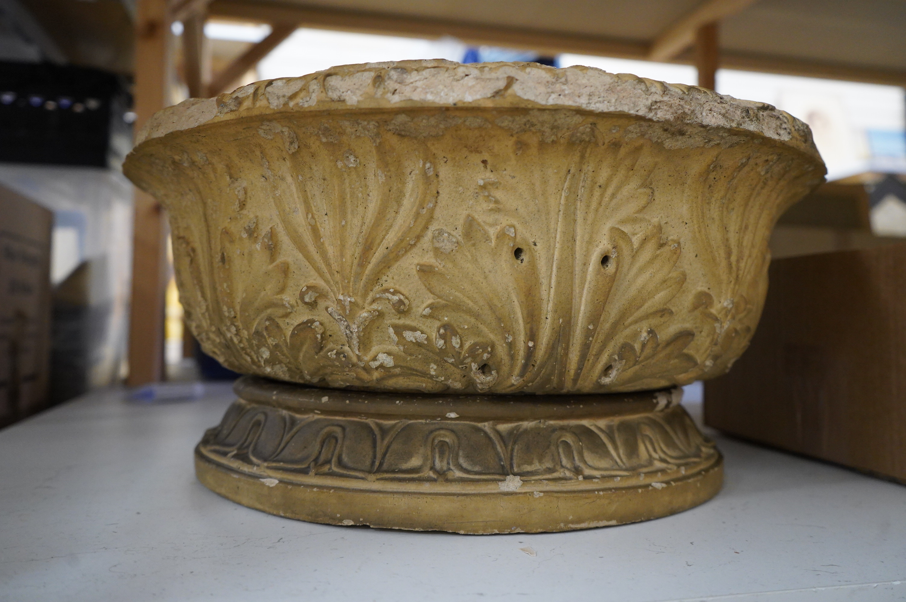 A buff coloured weathered earthenware jardiniere on stand, 48cm diameter
